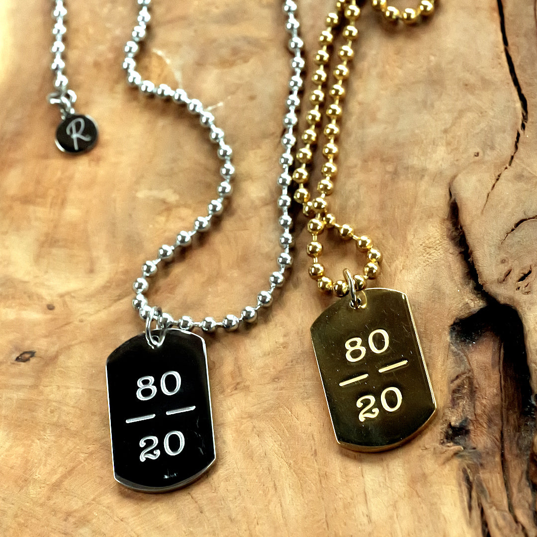 Two necklaces with dog tag pendants on a wooden surface, engraved with 80-20
